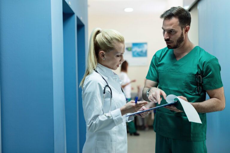 surgeon and female doctor going through patient s medical record while standing hospital lobby scaled 1